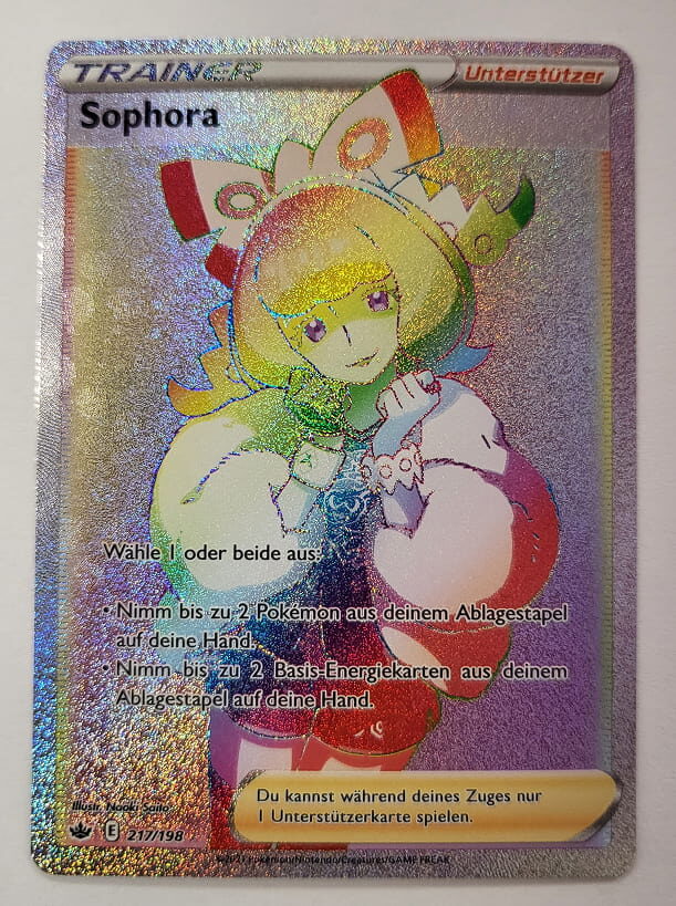 Holografische Rainbow-Trainerkarte von Sophora aus dem Pokémon-Sammelkartenspiel. Die Karte zeigt Sophora mit buntem, regenbogenfarbenem Schimmer-Effekt. Als Unterstützerkarte erlaubt sie dem Spieler, bis zu zwei Pokémon oder Basis-Energiekarten aus dem Ablagestapel auf die Hand zu nehmen.